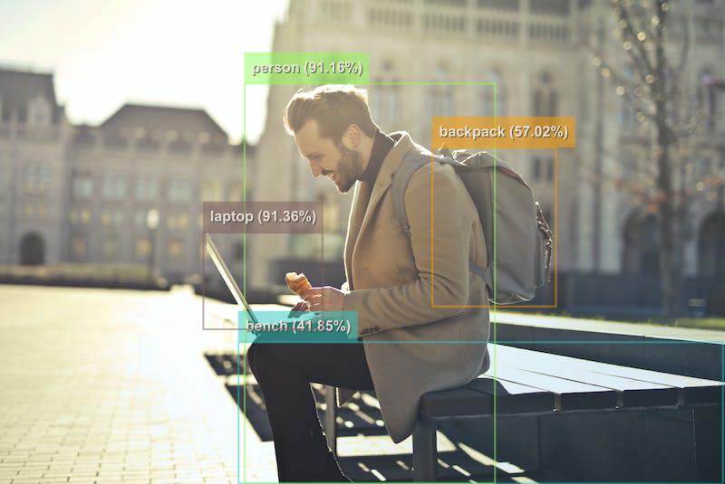 A man sitting on a bench with a laptop